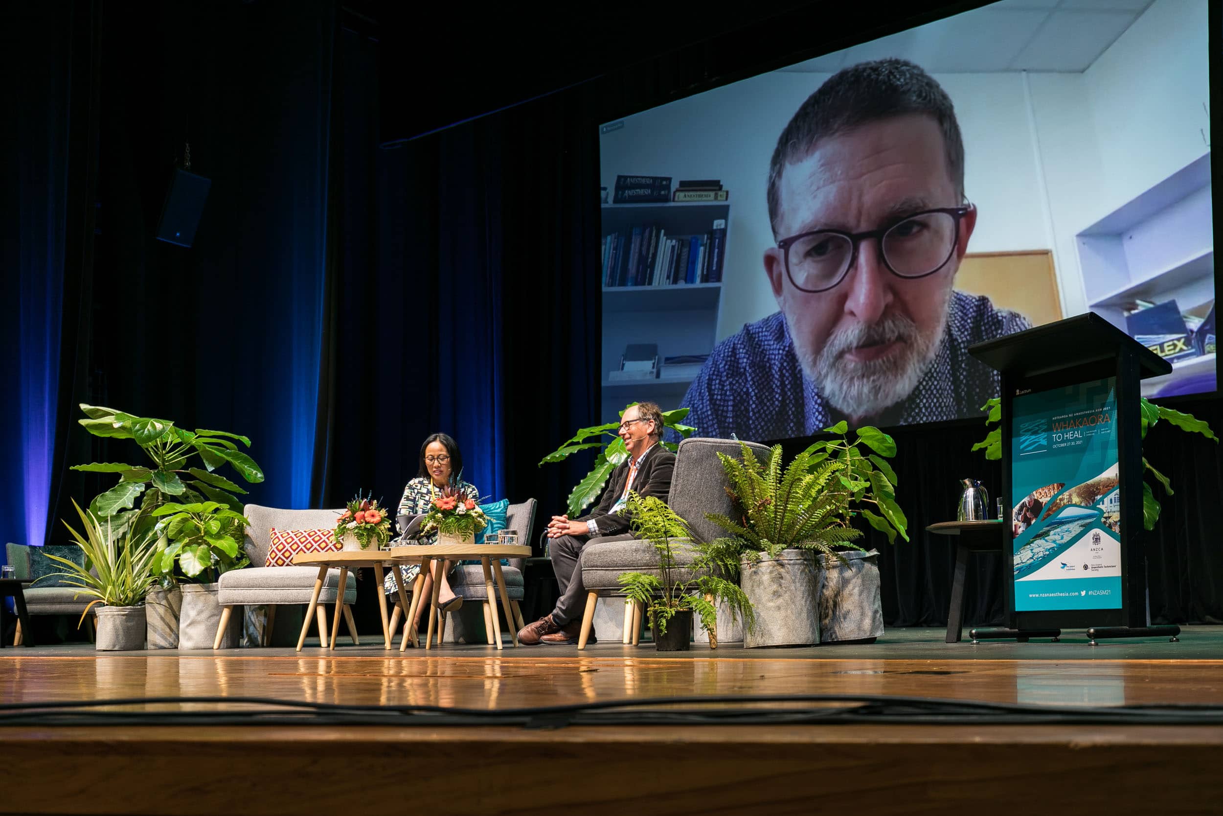 Guest presenter joins stage speakers remotely on screen during conference session Te Pae Christchurch.