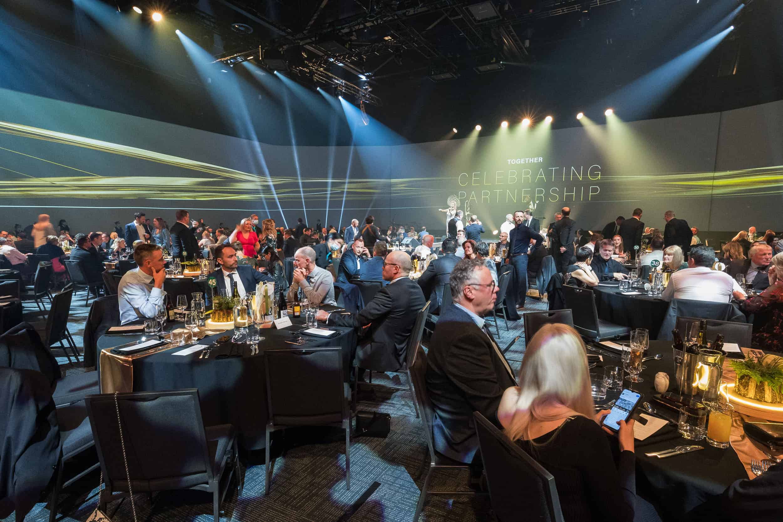 Conference dinner guests seated at round tables enjoy background entertainment at Te Pae.