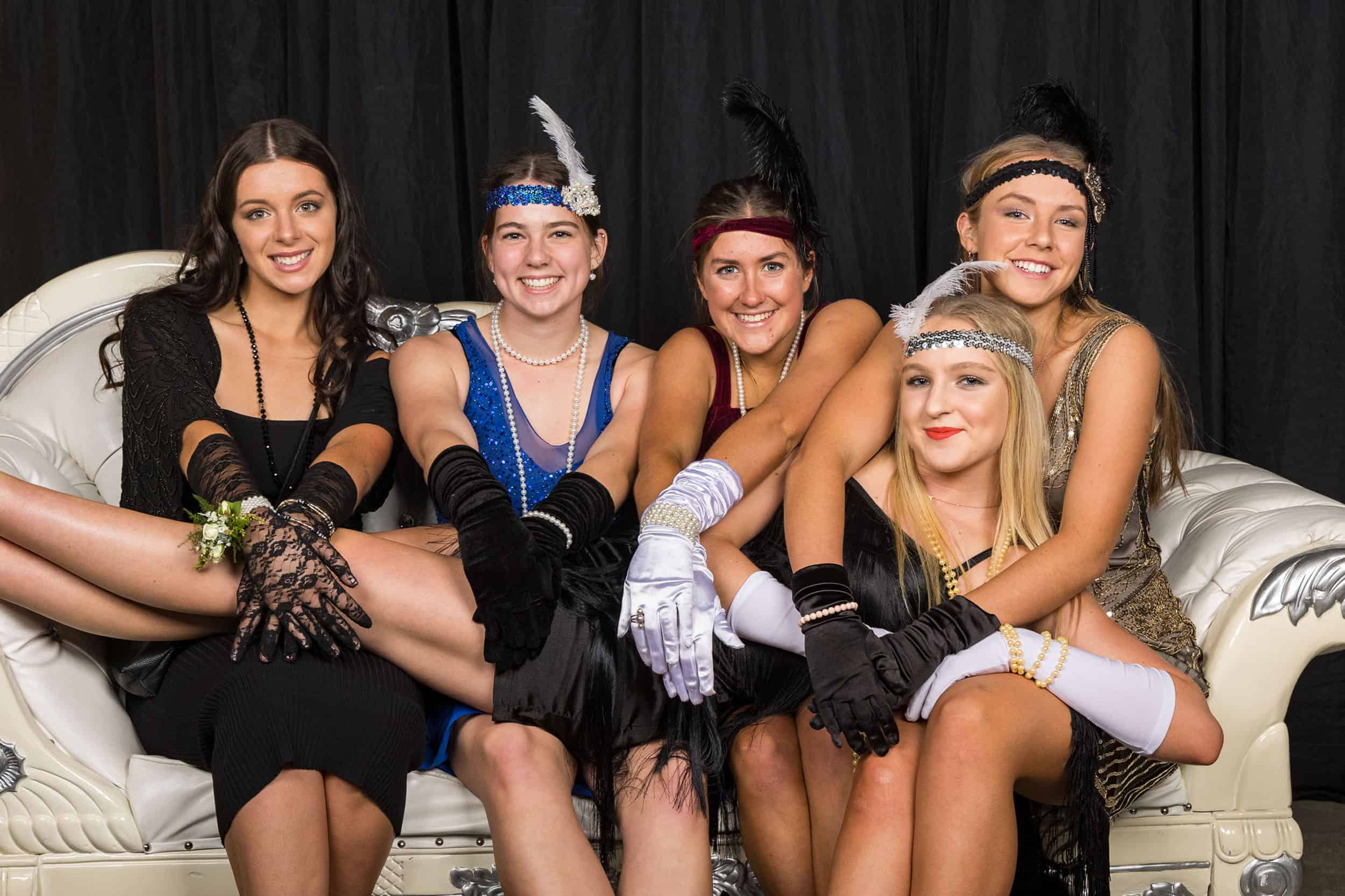 Five teenage girls on couch at school ball with Great Gadsby 1920's theme.