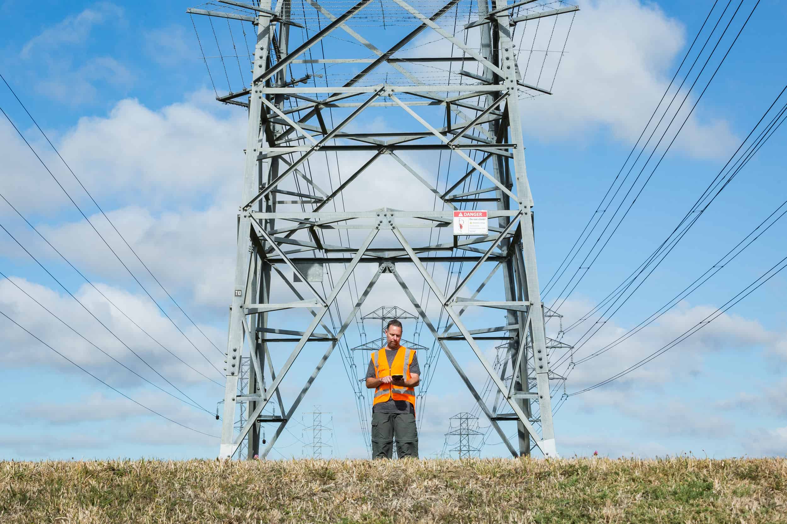 Surveyor uses handheld device plotting electrical pylon assets, Hei Hei.