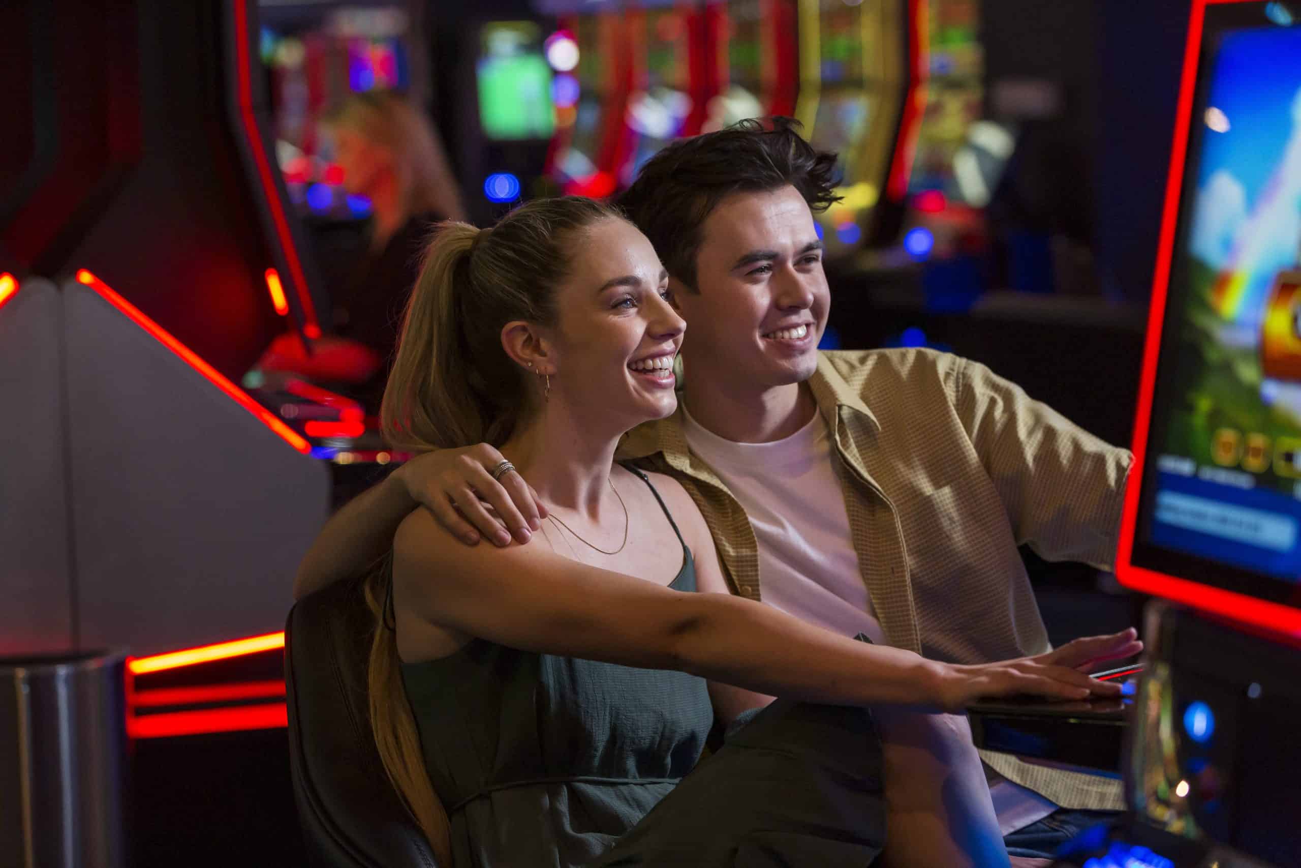 Young couple in their 20's enjoy playing pokie machines at Christchurch Casino.