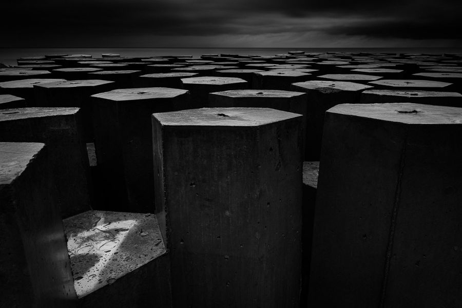 Moody fine art black and white photo of breakwater bollards.